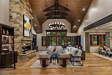 Inspiration for a huge rustic open concept medium tone wood floor and brown floor living room remodel in Phoenix with white walls, a ribbon fireplace, a stone fireplace and a wall-mounted tv