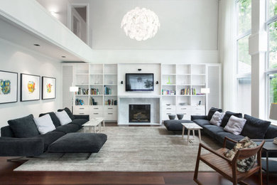 Ejemplo de salón abierto actual con paredes blancas, suelo de madera oscura, todas las chimeneas y televisor colgado en la pared