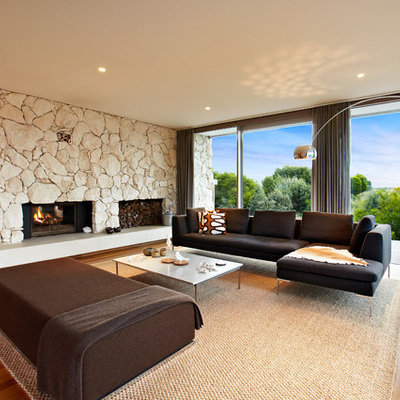 Example of a large 1960s formal and open concept medium tone wood floor living room design in Melbourne with a standard fireplace and a stone fireplace