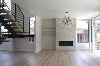 Inspiration for a huge modern formal and open concept light wood floor and brown floor living room remodel in San Francisco with white walls, a standard fireplace, a stone fireplace and no tv