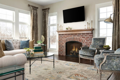 ミネアポリスにある高級な広いトラディショナルスタイルのおしゃれなリビング (ベージュの壁、無垢フローリング、標準型暖炉、レンガの暖炉まわり、壁掛け型テレビ、茶色い床) の写真