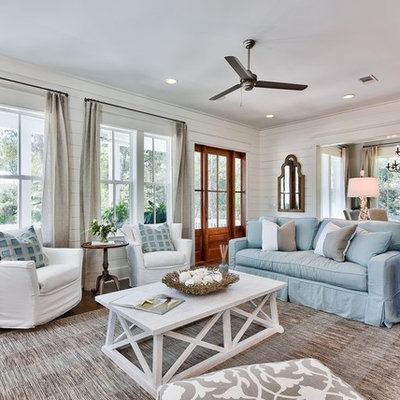 Large beach style open concept medium tone wood floor living room photo in Miami with white walls, a standard fireplace and a wall-mounted tv