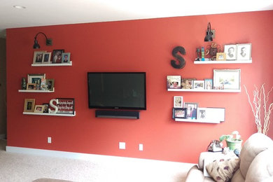 グランドラピッズにあるお手頃価格の中くらいなトラディショナルスタイルのおしゃれなリビング (赤い壁、カーペット敷き、壁掛け型テレビ) の写真