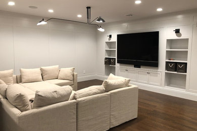 Mittelgroßes, Offenes Klassisches Wohnzimmer ohne Kamin mit grauer Wandfarbe, braunem Holzboden, TV-Wand und braunem Boden in New York