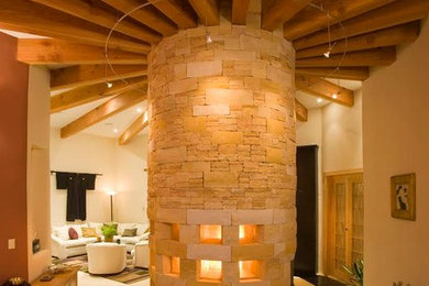 Example of a large southwest open concept limestone floor and beige floor living room design in Denver with beige walls and a stone fireplace