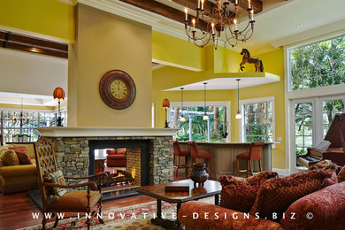 Foto de salón para visitas abierto tradicional extra grande con paredes amarillas, suelo de madera oscura, chimenea de doble cara, marco de chimenea de piedra y pared multimedia