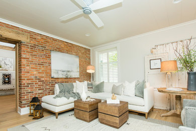 This is an example of a farmhouse living room in Columbus with light hardwood flooring, brown floors and white walls.