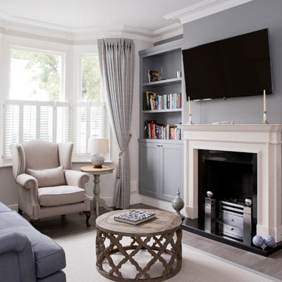 Example of a small transitional formal and enclosed brown floor and medium tone wood floor living room design in Wiltshire with a standard fireplace, a stone fireplace, a wall-mounted tv and white walls