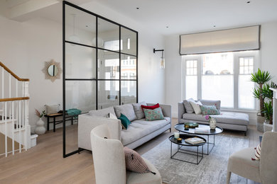 Large contemporary formal open plan living room in London with white walls, light hardwood flooring, a standard fireplace, a stone fireplace surround, no tv and beige floors.