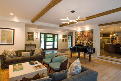 Example of a large eclectic open concept medium tone wood floor and brown floor living room design in Milwaukee with white walls, a standard fireplace and a concrete fireplace