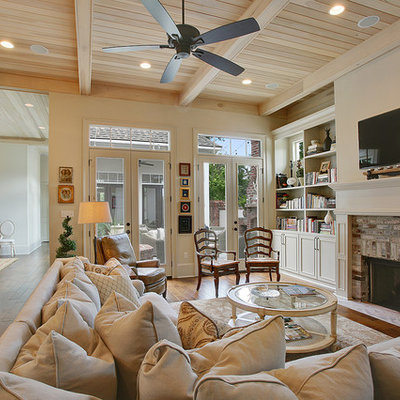 Living room - mid-sized traditional open concept dark wood floor living room idea in New Orleans with beige walls, a standard fireplace, a brick fireplace and a wall-mounted tv