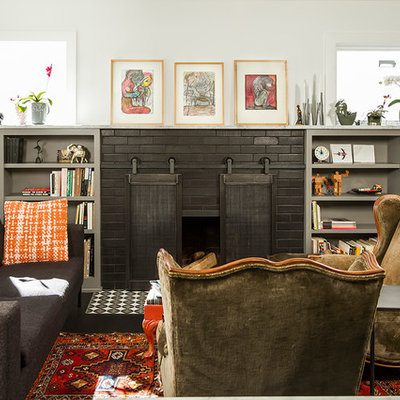 Example of an eclectic dark wood floor living room library design in Minneapolis with white walls, a standard fireplace and a brick fireplace