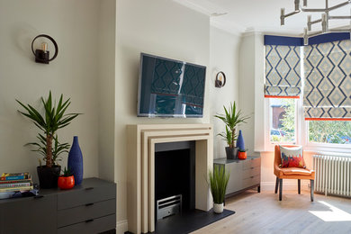 Bild på ett stort funkis loftrum, med ett finrum, grå väggar, ljust trägolv, en standard öppen spis, en spiselkrans i sten, en väggmonterad TV och beiget golv