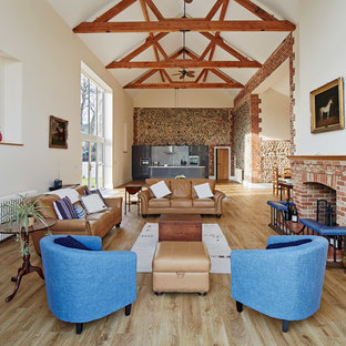 Inspiration for a large country formal open plan living room in Other with white walls, a standard fireplace, a brick fireplace surround, light hardwood flooring and beige floors.