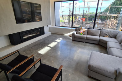 Example of a mid-sized trendy enclosed concrete floor and gray floor living room design in Melbourne with white walls, a standard fireplace and a concrete fireplace