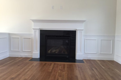 Example of a mid-sized classic formal and open concept medium tone wood floor living room design in Boston with beige walls, a standard fireplace, a wood fireplace surround and no tv
