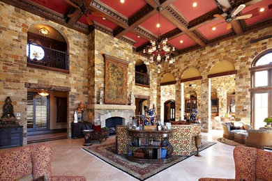 Ejemplo de salón abierto de estilo americano grande con todas las chimeneas, marco de chimenea de ladrillo, paredes beige y suelo de piedra caliza