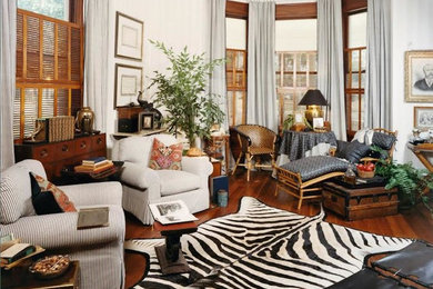 Ejemplo de salón para visitas cerrado tropical de tamaño medio con paredes blancas, suelo de madera en tonos medios y suelo marrón