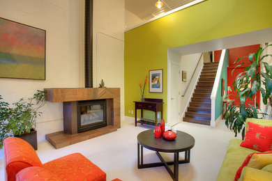 シアトルにある中くらいなインダストリアルスタイルのおしゃれなLDK (緑の壁、カーペット敷き、標準型暖炉、石材の暖炉まわり、テレビなし) の写真