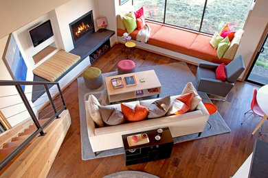 Eclectic open concept medium tone wood floor and orange floor living room photo in San Francisco with beige walls, a standard fireplace and a wall-mounted tv