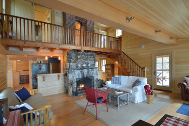 This is an example of a large rustic formal open plan living room in Portland Maine with brown walls, light hardwood flooring, a standard fireplace, a stone fireplace surround and no tv.
