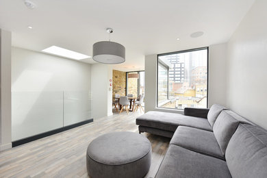 This is an example of a medium sized modern formal open plan living room in London with white walls, medium hardwood flooring, no fireplace, a freestanding tv and multi-coloured floors.