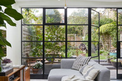 Photo of a medium sized contemporary open plan living room in London with white walls, concrete flooring and a wall mounted tv.