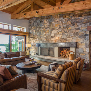 Mountain style open concept medium tone wood floor living room photo in Seattle with beige walls, a wood stove and a stone fireplace