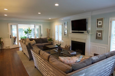 Example of a mid-sized transitional open concept medium tone wood floor living room design in Louisville with blue walls, a standard fireplace, a wood fireplace surround and a wall-mounted tv