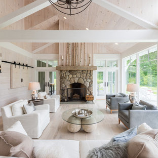 Idee per un grande soggiorno country aperto con sala formale, pareti beige, parquet chiaro, camino classico, cornice del camino in pietra, TV nascosta e pavimento beige