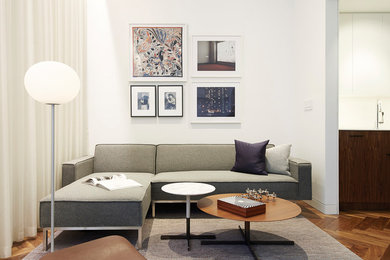 Diseño de salón abierto moderno de tamaño medio sin chimenea con suelo de madera en tonos medios, suelo marrón, paredes blancas y televisor independiente