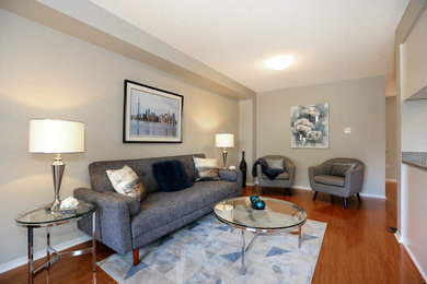 Example of a small trendy open concept medium tone wood floor and brown floor living room design in Toronto with gray walls, no tv, a corner fireplace and a wood fireplace surround