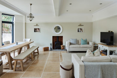 ロンドンにある高級な広いトラディショナルスタイルのおしゃれなLDK (グレーの壁、ライムストーンの床、薪ストーブ、漆喰の暖炉まわり、据え置き型テレビ、ベージュの床、格子天井、白い天井) の写真