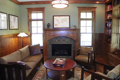 Example of a mid-sized arts and crafts enclosed medium tone wood floor living room library design in Chicago with green walls, a standard fireplace, a tile fireplace and no tv