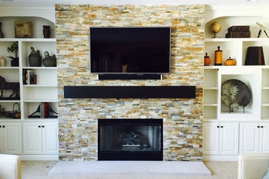 グランドラピッズにある広いトランジショナルスタイルのおしゃれなLDK (白い壁、カーペット敷き、標準型暖炉、石材の暖炉まわり、壁掛け型テレビ) の写真