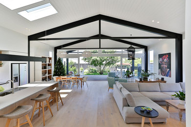 Großes, Offenes Klassisches Wohnzimmer mit weißer Wandfarbe, hellem Holzboden, Gaskamin, TV-Wand und braunem Boden in Auckland