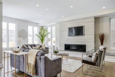 Großes, Offenes Modernes Wohnzimmer mit grauer Wandfarbe, braunem Holzboden, Gaskamin, gefliester Kaminumrandung, TV-Wand und beigem Boden in Ottawa