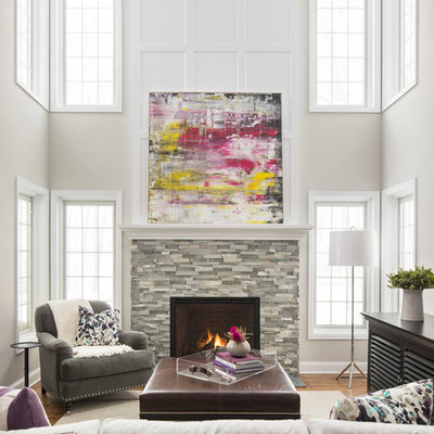 Example of a large transitional medium tone wood floor and brown floor living room design in Minneapolis with a standard fireplace, a stone fireplace, beige walls and no tv