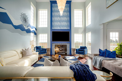 Ejemplo de salón abierto tradicional renovado con paredes azules, suelo de madera en tonos medios, todas las chimeneas, marco de chimenea de baldosas y/o azulejos, televisor colgado en la pared y suelo marrón