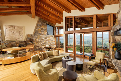 Offenes Modernes Wohnzimmer mit hellem Holzboden, Kaminumrandung aus Stein und verstecktem TV in Denver