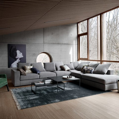 Example of a large urban open concept medium tone wood floor living room design in Manchester with gray walls