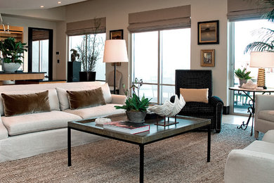 Imagen de salón abierto tradicional renovado con paredes beige, suelo de madera clara y televisor retractable