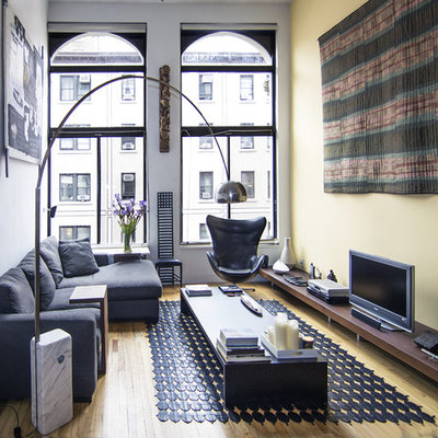 Example of a small minimalist formal medium tone wood floor and brown floor living room design in New York with a tv stand, yellow walls and no fireplace