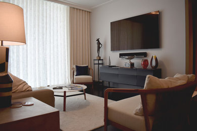 Immagine di un soggiorno eclettico di medie dimensioni e aperto con pareti grigie, parquet scuro, TV a parete e pavimento nero