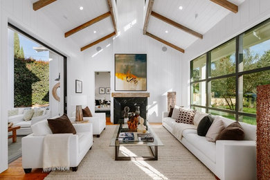 Imagen de salón de estilo de casa de campo con paredes blancas, suelo de madera en tonos medios, todas las chimeneas, marco de chimenea de piedra y suelo marrón