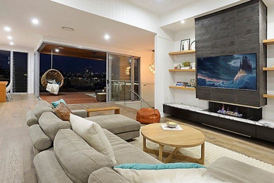 Medium sized contemporary open plan living room in Brisbane with light hardwood flooring, a stone fireplace surround and a built-in media unit.