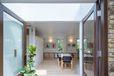 Diseño de salón cerrado actual de tamaño medio con paredes blancas y suelo de madera clara