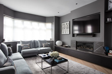 Aménagement d'un salon contemporain avec un mur gris, un manteau de cheminée en pierre et un téléviseur fixé au mur.
