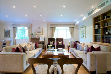 Example of a large trendy open concept medium tone wood floor living room design in London with beige walls