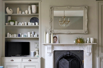 ロンドンにあるお手頃価格の中くらいなヴィクトリアン調のおしゃれなリビング (グレーの壁、塗装フローリング、標準型暖炉、石材の暖炉まわり、据え置き型テレビ、白い床) の写真